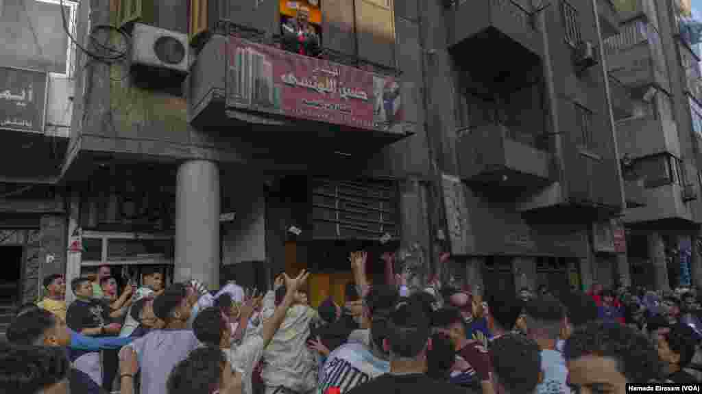 As part of his own Eid tradition, a real estate businessman throws handfuls of one Egyptian pound banknotes from his office window after Eid prayers, across from the Mosque of Sultan Hassan.