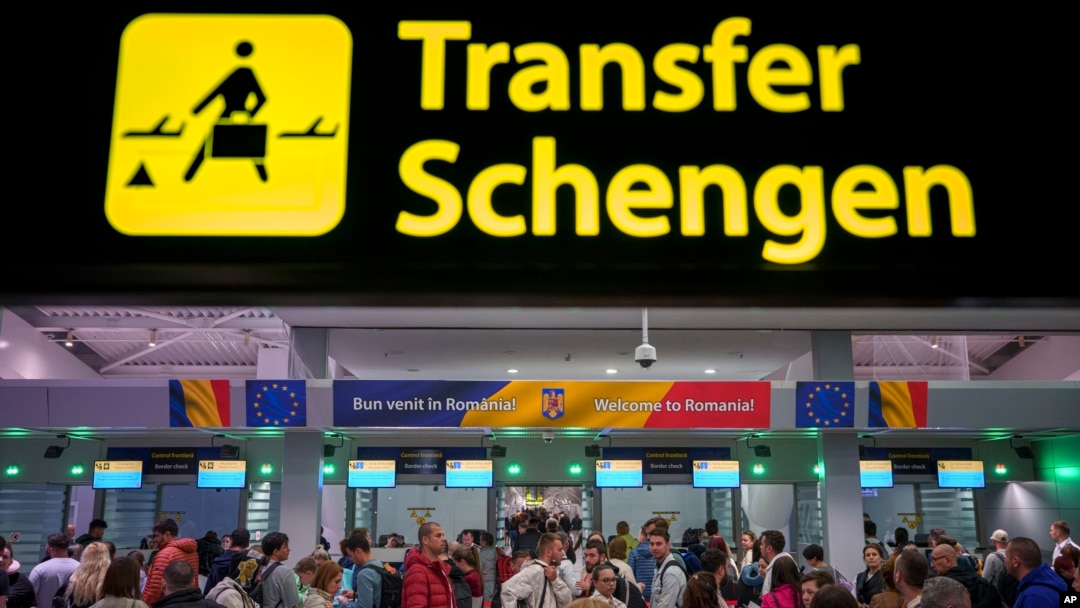 Passengers arriving at Henri Coanda International Airport pass under a Schengen zone transfer sign, in Otopeni, near Bucharest, Romania, March 31, 2024. 