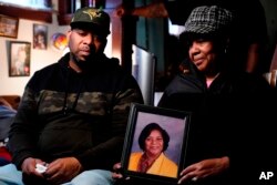 Wayne Jones, left, looks on as his aunt JoAnn Daniels holds a photograph of his mother, Celestine Chaney, who was killed in a shooting at a supermarket in Buffalo, N.Y., May 16, 2022.