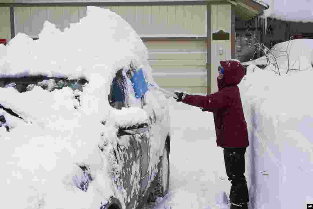 Patty Roberts shovels snow from her car on her driveway during a storm, March 2, 2024, in Truckee, California.