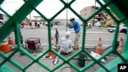 Workers set up a barricade near the Lawson convenience store, background, Tuesday, April 30, 2024, at Fujikawaguchiko town, central Japan. (AP Photo/Eugene Hoshiko)