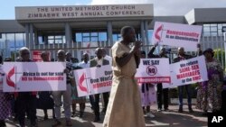 Membros da Igreja Metodista Unida do Zimbabwe seguram cartazes durante um protesto nas instalações da igreja em Harare, quinta-feira, 30 de maio de 2024.