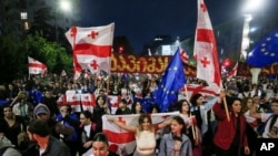 FILE - Demonstrators with Georgian national and EU flags rally during an opposition protest against a foreign influence bill as they mark their country's Independence Day, in the center of in Tbilisi, Georgia, May 26, 2024.