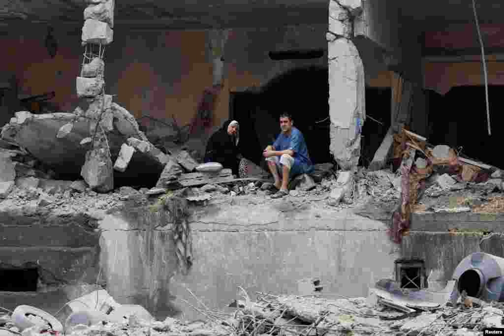 Palestinians sit among the rubble of a damaged residential building in the aftermath of Israeli strikes in Gaza City. REUTERS/Mohammed Salem