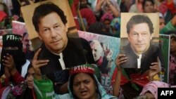 FILE - Supporters of Pakistan's former prime minister Imran Khan carry placards displaying a portrait of Khan in Karachi, March 19, 2023. Pakistan's political and judicial crisis began with Khan's removal from office in a parliamentary vote of no-confidence last April.