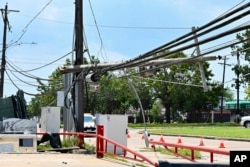 FILE - Utility polls wait for repair after being damaged by Hurricane Beryl in Houston, July 10, 2024.