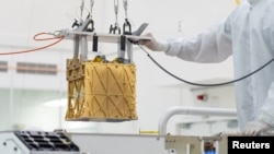 Technicians at NASA's Jet Propulsion Laboratory lower the MOXIE instrument into the belly of the Perseverance rover in an undated photograph in Pasadena, California. (NASA/JPL-Caltech/Handout via REUTERS)