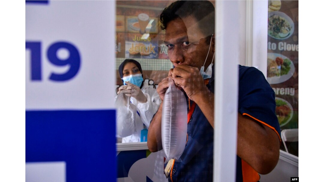 FILE - Seorang pria meniup kantong nafas untuk tes GeNose C19 untuk screening virus corona COVID-19 di Bandara Internasional Sultan Iskandar Muda di Blang Bintang, 25 April 2021. (CHAIDEER MAHYUDDIN/AFP)