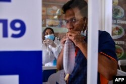 FILE - Seorang pria meniup kantong nafas untuk tes GeNose C19 untuk screening virus corona COVID-19 di Bandara Internasional Sultan Iskandar Muda di Blang Bintang, 25 April 2021. (CHAIDEER MAHYUDDIN/AFP)