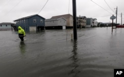 FILE - A Dare County utility worker checks on conditions along a flooded Ride Lane in Kitty Hawk, N.C., Monday, Oct. 29, 2012, as the effects of Hurricane Sandy are visible along the east coast. (AP Photo/Gerry Broome, File)