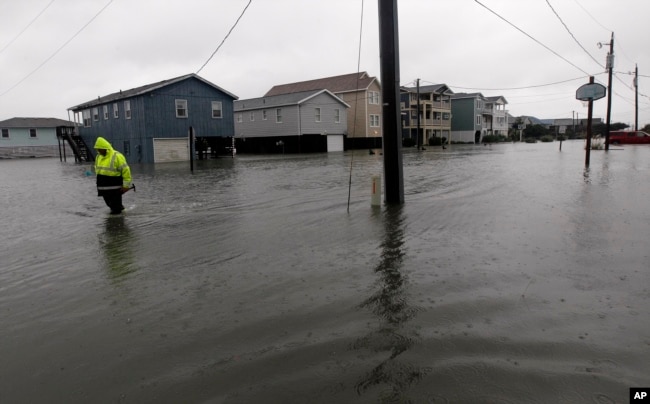 FILE - A Dare County utility worker checks on conditions along a flooded Ride Lane in Kitty Hawk, N.C., Monday, Oct. 29, 2012, as the effects of Hurricane Sandy are visible along the east coast. (AP Photo/Gerry Broome, File)