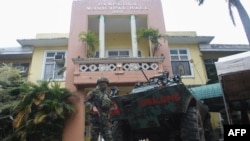 An armed member of the police Special Action Force (SAF) stands guard in front of the municipal hall in Pamplona town in Negros Oriental on March 5, 2023, a day after provincial governor Roel Degamo and eight others were killed in a mass shooting. 