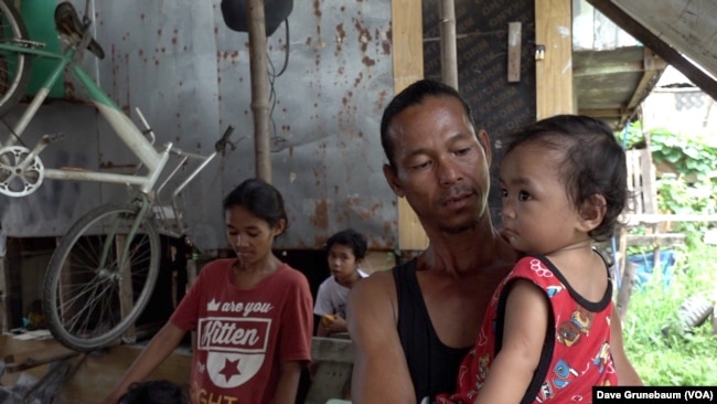 In Taguig, Philippines, May 18, 2023, parent Joeson Dalanon holds his one-year-old son Nick Maron. Dalanon told VOA “I hear there are lots of kids who die” from vaccines.