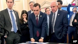 U.S. Representatives — from left, Jake Auchincloss, Haley Stevens, Mike Gallagher, and Carlos Gimenez — gather for a tabletop war game exercise April 19, 2023, in Washington. The lawmakers serve on a new House select committee on China. Mike Gallagher serves as chair.