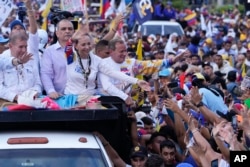 Presidential candidate Edmundo Gonzalez, left, and opposition leader Maria Corina Machado, center, greet supporters during a campaign rally in Maracaibo, Venezuela, July 23, 2024.