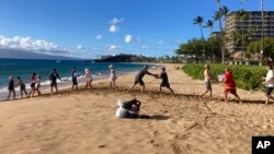 FILE - A group of volunteers who sailed from Maalaea Bay, Maui, form an assembly line on Kaanapali Beach on Aug. 12, 2023, to unload donations from a boat.