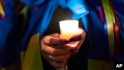 Demonstrator Sofia Koukhanova holds candles during a rally in support of Ukraine outside of the Russian Embassy in Washington, Feb. 24, 2023. 