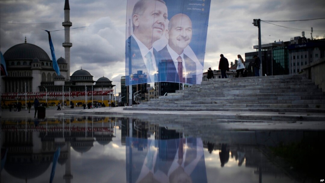 Pedestrians walk past a giant banner of Turkish President and People's Alliance's presidential candidate Recep Tayyip Erdogan, left, at Taksim Square in Istanbul, Turkey, May 10, 2023.