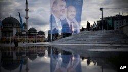 Pedestrians walk past a giant banner of Turkish President and People's Alliance's presidential candidate Recep Tayyip Erdogan, left, at Taksim Square in Istanbul, Turkey, May 10, 2023.