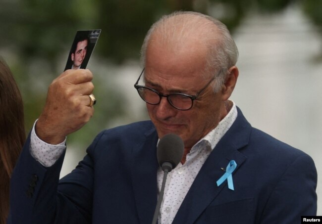 A father holds his son's picture as he attends a ceremony marking the 21st anniversary of the September 11, 2001 attacks on the World Trade Center at the 9/11 Memorial and Museum in the Manhattan borough of New York City, Sept. 11, 2022.