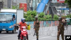 A scooterist asks Bangladeshi military forces soldiers patrolling a street which way is open to travel, in Dhaka, July 22, 2024.