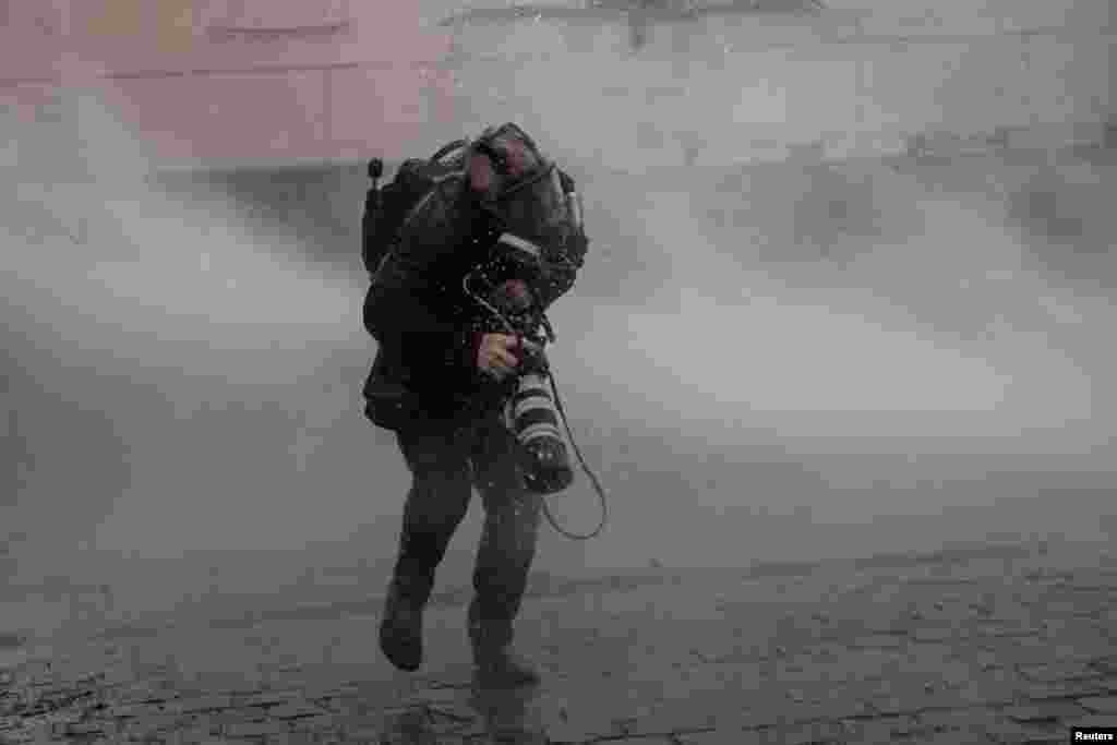 Getty Images photographer John Moore gets hit by a water cannon during clashes with riot police at a rally-march ahead of the 50th anniversary of the 1973 Chilean military coup, in Santiago, Chile, Sept. 10, 2023.