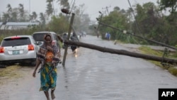 This handout photograph taken and distributed by UNICEF on March 12, 2023 shows a woman walking along a street damaged by the impact of Cyclone Freddy in the city of Quelimane.