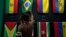 An indigenous man passes his hand over the Brazilian flag in a flag pavilion of the States parties to the Amazon Cooperation Treaty, during the Amazon Dialogue meetings at the Hangar convention center in Belem, Brazil, Aug. 6, 2023. 