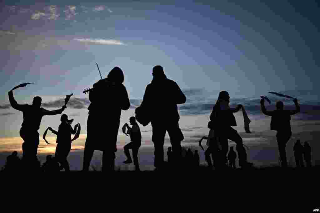 Kelompok tari Miserden Morris tampil pada perayaan May Day, saat matahari terbit di Rodborough Common, Stroud, Inggris bagian barat, 1 Mei 2024. (Ben STANSALL / AFP)