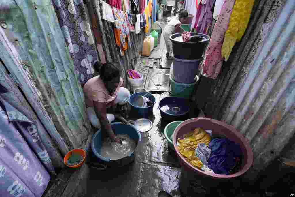 En Mumbai, India, una mujer lava utensilios de cocina en baldes ubicados afuera de su vivienda en una zona humilde de la ciudad.