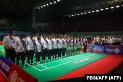 Para pemain dan pelatih bulutangkis China (berjaket putih dan ban lengan hitam), beserta seluruh pemain yang berlaga di Kejuaraan Junior Asia 2024, berdoa bersama untuk mendiang Zhang Zhijie. (Foto: via AFP)