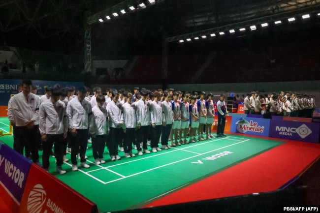 Para pemain dan pelatih bulutangkis China (berjaket putih dan ban lengan hitam), beserta seluruh pemain yang berlaga di Kejuaraan Junior Asia 2024, berdoa bersama untuk mendiang Zhang Zhijie. (Foto: via AFP)