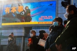 Residents wait to cross a street near a screen promoting the Chinese People's Liberation Army Air Force, in Beijing, Jan. 9, 2023. The Chinese military held combat strike drills starting the day before, the Chinese and Taiwanese defense ministries said.