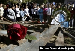 FILE - Students stand behind the wreckage of a gate at Athens Polytechnic, that was the center of an uprising in 1973 against the military dictatorship then ruling Greece, Nov. 16, 2006. (AP Photo/Petros Giannakouris, File)