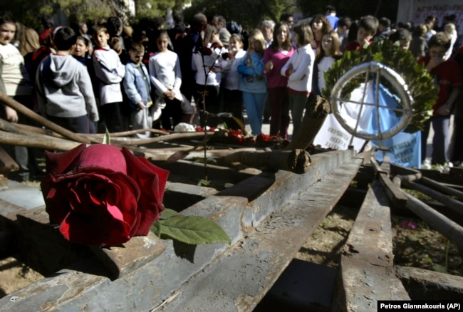 FILE - Students stand behind the wreckage of a gate at Athens Polytechnic, that was the center of an uprising in 1973 against the military dictatorship then ruling Greece, Nov. 16, 2006. (AP Photo/Petros Giannakouris, File)