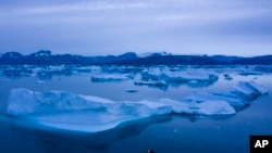 FILE - A boat navigates at night next to large icebergs near the town of Kulusuk, in eastern Greenland, Aug. 15, 2019.