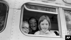 FILE - Children smile from window of a school bus in Springfield, Mass., as court-ordered busing brought Black children and white children together in elementary grades without incident, Sept. 16, 1974. 