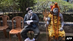 Artists dressed as Charlie Chaplin, left, and Hindu lord Shiva wait to perform during a program organized to create awareness about the traditional folk art form of polymorphic Bahuroopiya, in Kolkata, India.