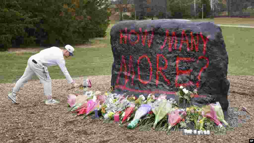 Seorang mahasiswa meninggalkan bunga di The Rock di halaman Michigan State University, di East Lansing, Michigan, 14 Februari 2023. Seorang pria bersenjata membunuh tiga mahasiswa dan melukai lima lainnya di kampus ini. Polisi mengatakan bahwa penembak akhirnya bunuh diri.