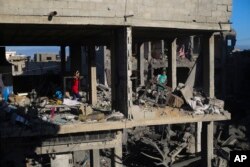 Palestinians look at the destruction after an Israeli strike on residential buildings in Rafah, Gaza Strip, Dec. 15, 2023.