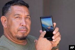 FILE - Shane Treu points to his phone while showing the video of the fire, in Wailuku, Hawaii, Aug. 15, 2023.