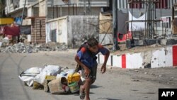 A Palestinian youth pulls salvaged items in Deir al-Balah in the central Gaza Strip amid the ongoing conflict between Israel and Hamas.