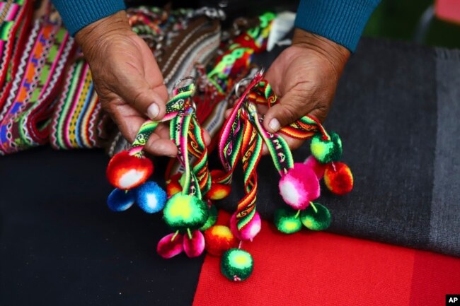 An Aymara Indigenous woman shows handwoven woolen crafts made on the sidelines of a fashion show showcasing Indigenous creations at Zofri Mall in Iquique, Chile, Saturday, July 29, 2023. (AP Photo/Ignacio Munoz)