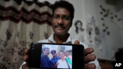 Gautam Dongre, of the National Alliance of Sickle Cell Organizations, shows a photograph his family, including his son, Girish, second left, and daughter, Sumedha, right, both patients with sickle cell disease, in Nagpur, India, Dec. 6, 2023.