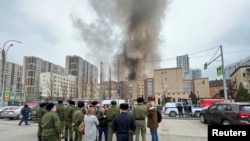 People gather in a street, as smoke rises near a building belonging to the border patrol section of Russia's FSB federal security service in the southern city of Rostov-on-Don, Russia, March 16, 2023. 