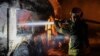In this photo provided by the Ukrainian Emergency Situations Ministry, a firefighter tries to put out fire caused by fragments of a Russian rocket after it was shot down by air defense system during a Russian rocket attack in Kyiv, Ukraine, May 16, 2023.