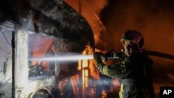 In this photo provided by the Ukrainian Emergency Situations Ministry, a firefighter tries to put out fire caused by fragments of a Russian rocket after it was shot down by air defense system during a Russian rocket attack in Kyiv, Ukraine, May 16, 2023.