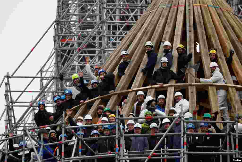 Carpenters and workers stand for a picture during the ceremony of the traditional bouquet of flowers to celebrate the end of the rebuilding of the medieval choir framework of the Notre-Dame de Paris Cathedral, which was badly damaged by a fire in 2019, in Paris, France.