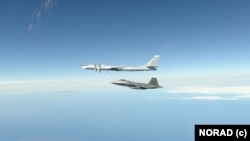 Pesawat tempur AS F-22 Raptor (bawah) mencegat pembom Tu-95 Rusia di Zona Identifikasi Pertahanan Area Alaska 16 Juni 2020 (foto: dok). 