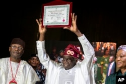FILE - President-elect Bola Tinubu, center, displays his certificate, accompanied by his wife Oluremi Tinubu, right, and chairman of the Independent National Electoral Commission Mahmood Yakubu at a ceremony in Abuja, Nigeria, March 1, 2023.